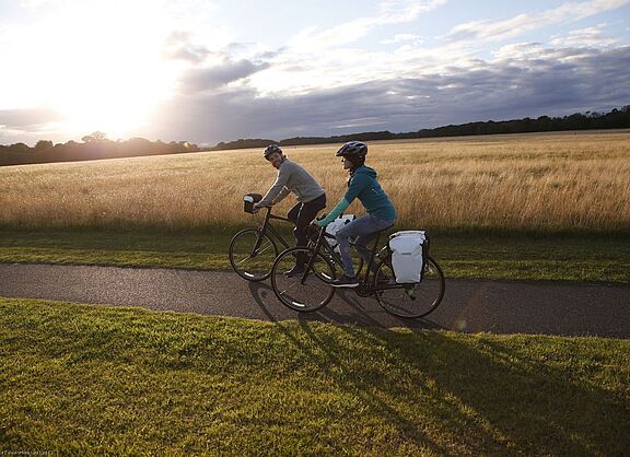 Radtour im Herbst Zwei Radfahrende auf Tour vor herbstlicher Kulisse im Gegenlicht.
